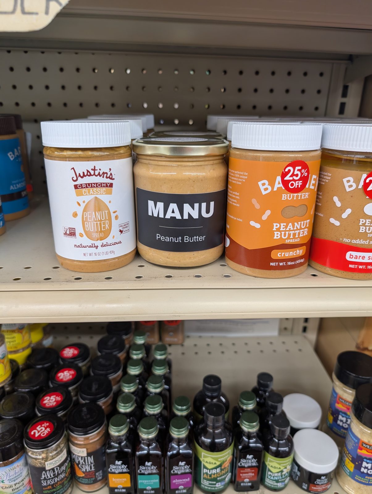 MANU peanut butter on a retail shelf beside other nut butter brands